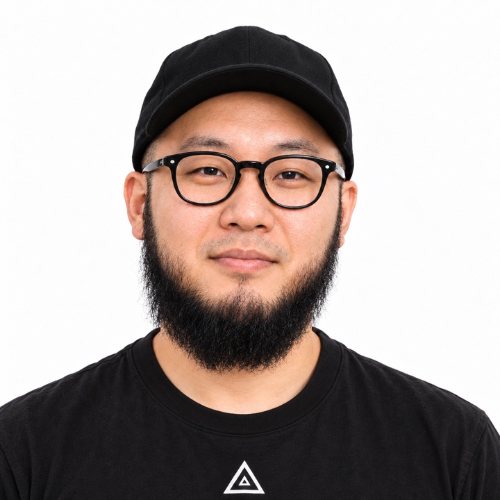 黒いキャップと眼鏡、髭が特徴のtomio